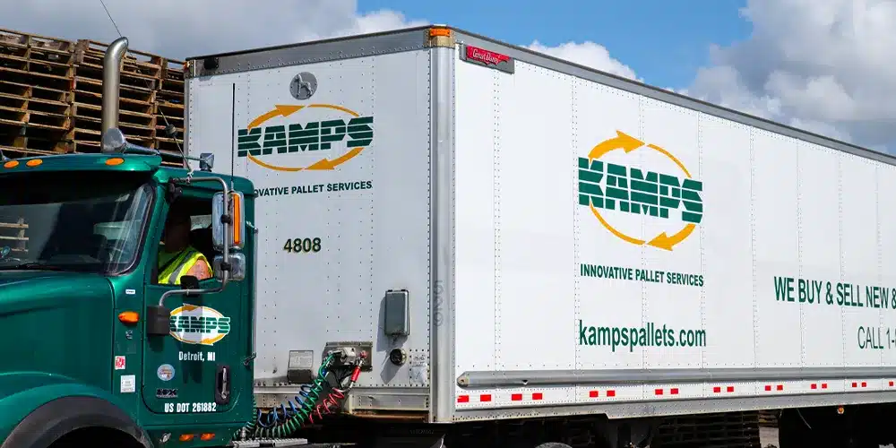 Kamps Truck and Trailer parked in front of a stack of pallets.