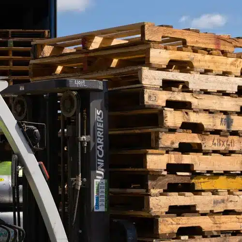 Stack of used wooden pallets on a forklift.