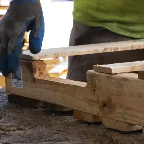 A man wearing a glove fitting the corner of a wooden board on top of a wooden stringer.