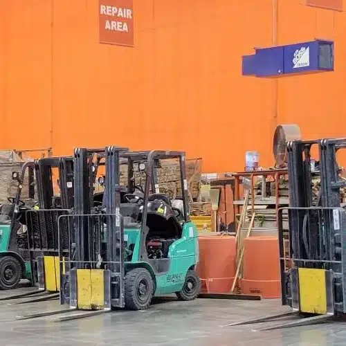 A row of forklifts with no operators neatly parked to one another