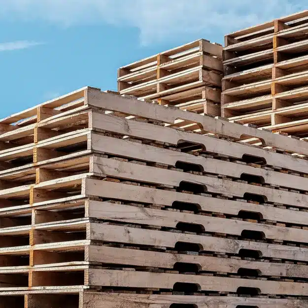 Angle view of three stacks of long, custom-designed, wooden pallets with notched stringers.