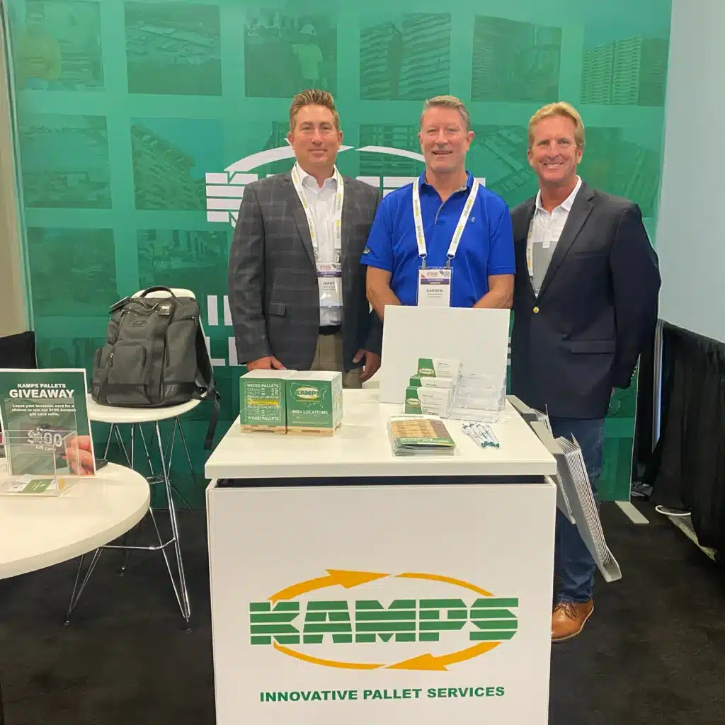 Three Kamps salespeople stand behind a Kamps branded white booth.